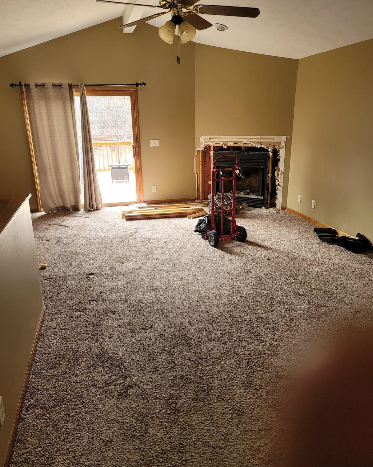 Before, a dated great room with worn carpet and a builder-grade fireplace ready for a remodel