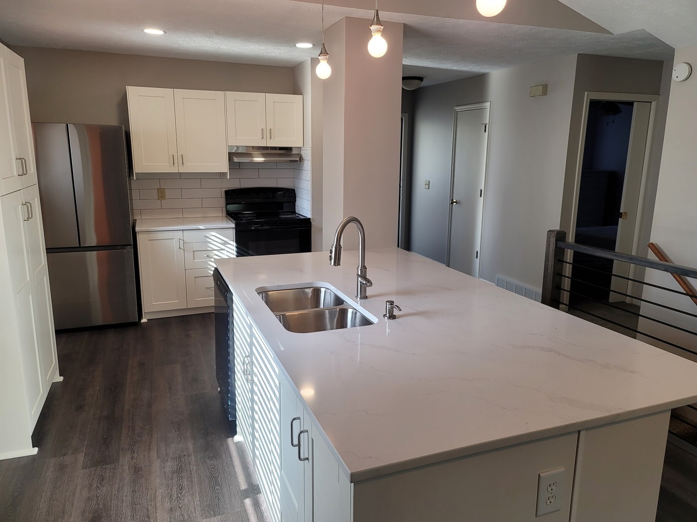 White cabinets, waterfall-quartz island by Hansen Construction, Bellevue